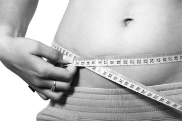 person holding tape measure across abdomen