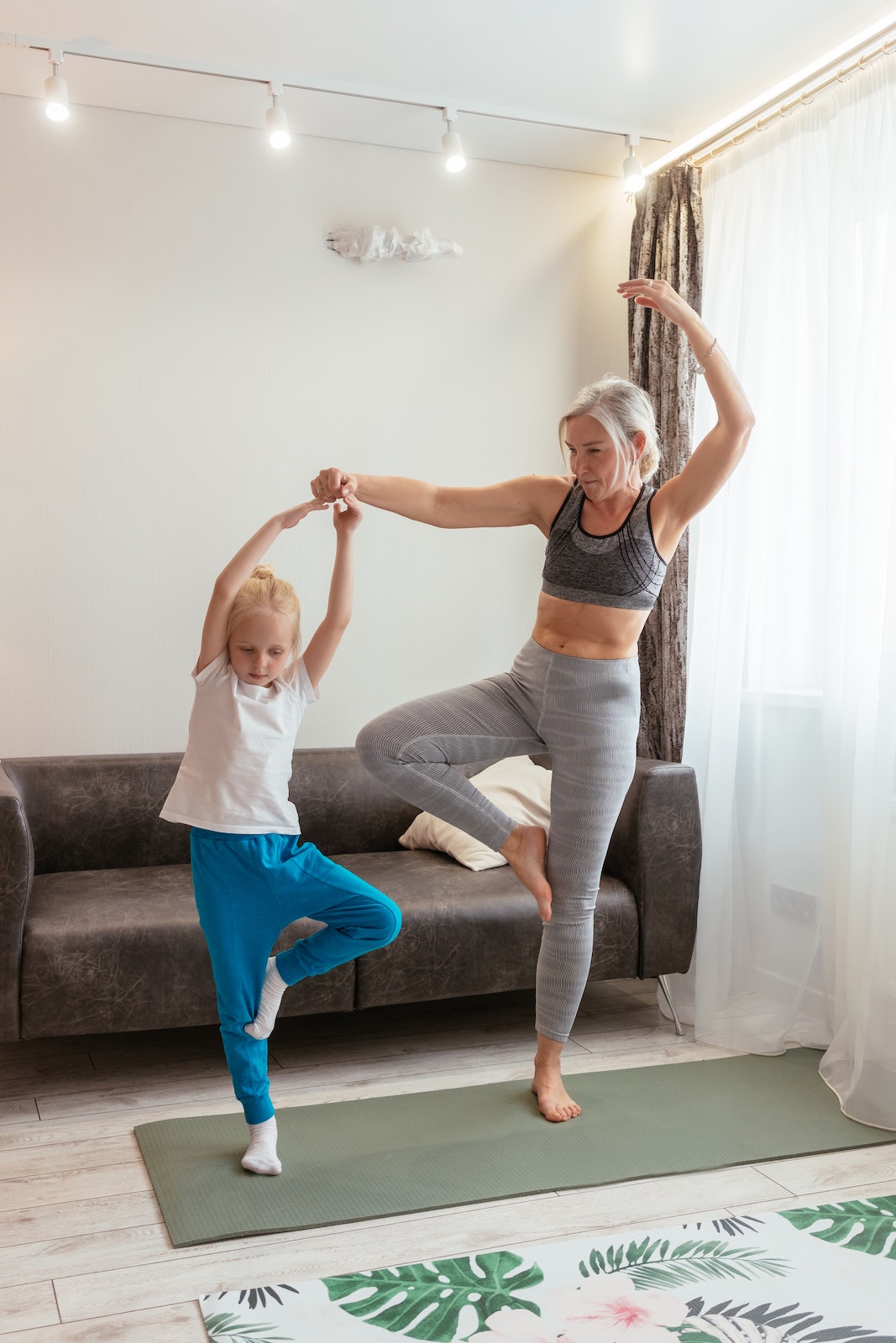 Fit grandma balancing on one leg with grandaughter